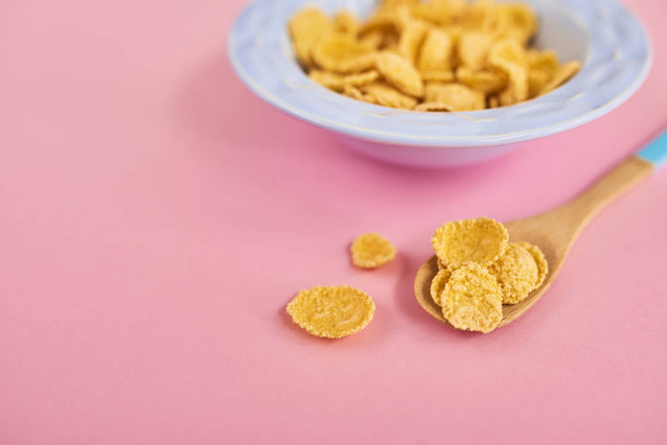 Blue plate of cereals and spoon on pink background, top view - Photo, image