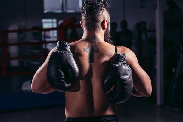 guy back towards camera, pair of boxing gloves over his shoulder - Fotografie, Obrázek
