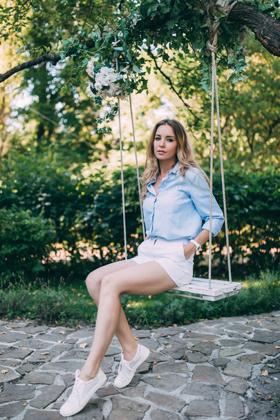 Girl in a blue shirt on a swing. - Foto, immagini