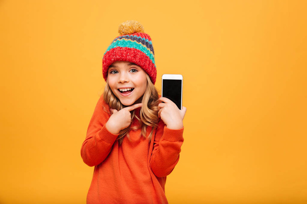 Surprised happy Young girl in hat showing blank smartphone screen - Fotoğraf, Görsel