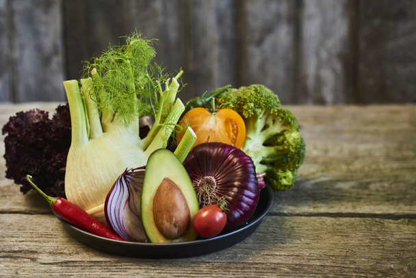 Тарелка с различным ассортиментом овощей на деревянном фоне
 - Фото, изображение