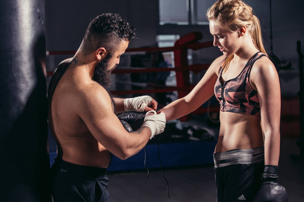 coach puts on boxing gloves athlete before the fight. Backlight. - 写真・画像
