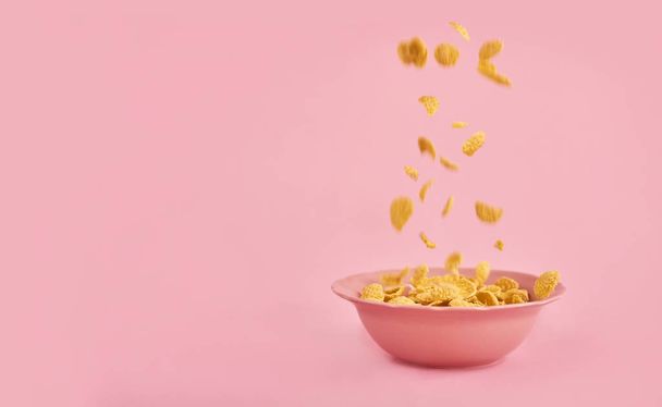Cereales cayendo sobre plato rosado sobre fondo rosado. maqueta de diseño con espacio para introducir el texto
 - Foto, Imagen