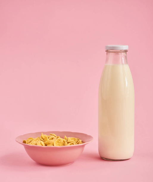 Pink plate with cereals and bottle of milk on pink background - Photo, Image