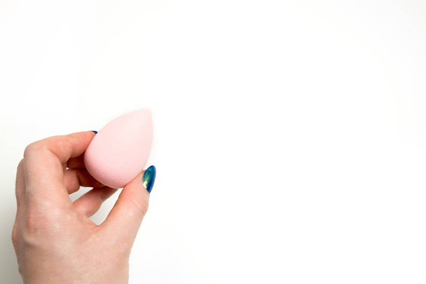 Female hand holding pink beauty sponge over a white background.  - Foto, imagen