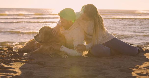 Couple With A Dog enjoying time  together On The Beach at autumn day - Foto, imagen