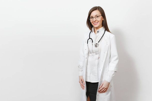 Улыбается уверенно красивая молодая женщина-врач со стетоскопом, очки изолированы на белом фоне. Женщина-врач в медицинском халате, выглядящая как камера. Здравоохранение, здравоохранение, медицина
. - Фото, изображение