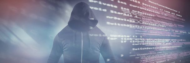 Male hacker wearing black hoodie while standing against code - Fotografie, Obrázek
