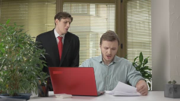 A young subordinate employee brought the boss a report, a document. Makes funny faces while the boss does not see, behind his back. Work in the office. 60 fps - Záběry, video