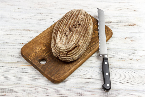 Pan de centeno fresco en la receta francesa en la tabla de cortar con cuchillo
 - Foto, Imagen