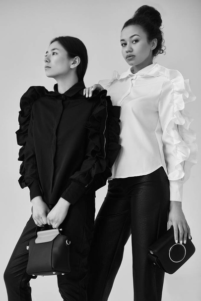 Élégant couple de femmes noires et asiatiques à la mode noir et
 - Photo, image