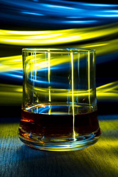 A glass of cognac on the table in night club with bokeh effect. - Фото, зображення