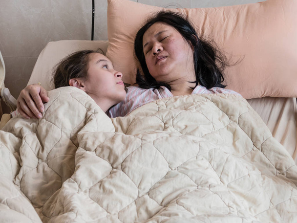 病気の母の横に病院のベッドの上に横たわる少女 - 写真・画像