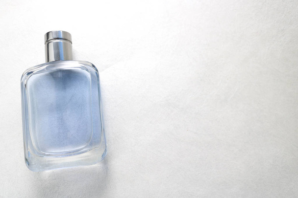 Blauwe rechthoekige mooie glazen transparante glanzende modieuze glamoureuze fles van Keulen, parfum met zilverkleurige bezel en plaats voor voorbeeldtekst op een grijze lichte achtergrond - Foto, afbeelding