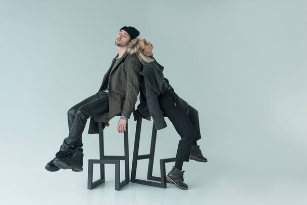 two stylish dancers sitting on stool at white background - Foto, imagen