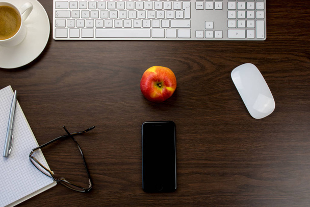 Schreibtisch im Büro mit Smartphone und rotem Apfel in der Mitte - Foto, Bild