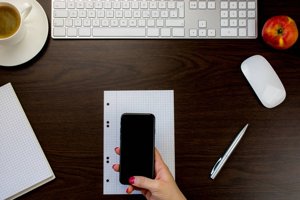 Schreibtisch im Büro mit Smartphone in der Hand und Tastatur n - Foto, Bild