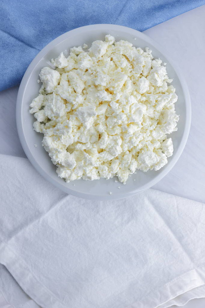 Cheese, cottage cheese on a white plate, fresh cottage cheese on a white and blue napkin, dairy product on a white background, healthy food, French breakfast, top view, goat curd in minimalist style, protein - Foto, Imagem