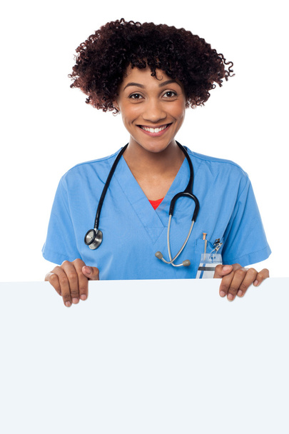 Joyous female doctor standing behind ad board - Foto, Bild