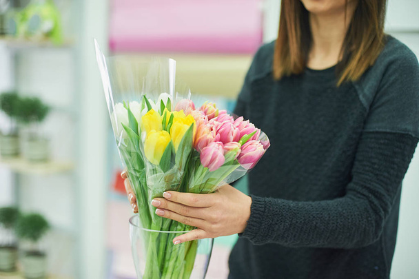 Close-up hands of florist with flowers. Florist holding blooming bouquet of pink tulips on a linen background. - Φωτογραφία, εικόνα