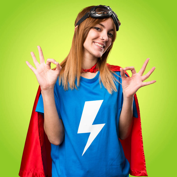 Szép superhero lány így az Ok jel színes háttérrel - Fotó, kép