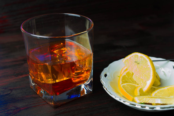 A glass of alcohol and sliced lemon. - Zdjęcie, obraz