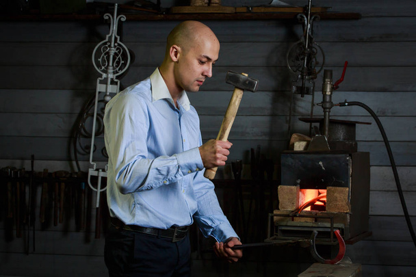 Man in a business suit forging  by hammering on the anvil - Photo, image