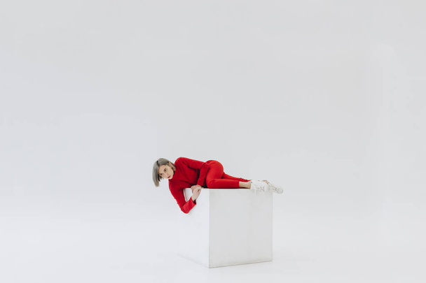woman in red clothes on white cube - Фото, изображение
