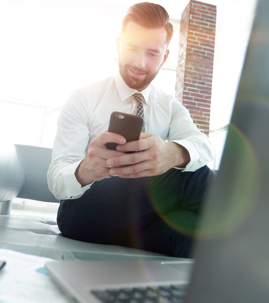 Businessman looking at screen smartphone sitting in front of an  - Foto, Imagen