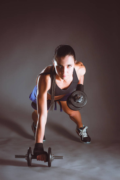 Young woman doing exercise with dumbbells - Foto, afbeelding