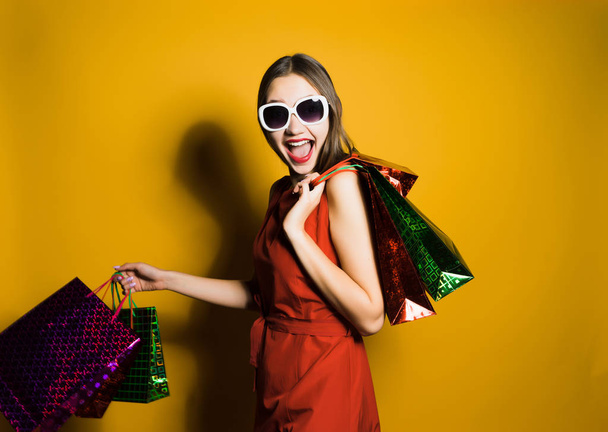 happy woman with glasses holds packages with purchases in hands and posing on camera - Foto, Imagem