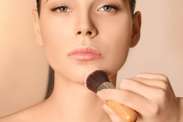 Professional visage artist applying makeup on woman's face against light background - Foto, Bild
