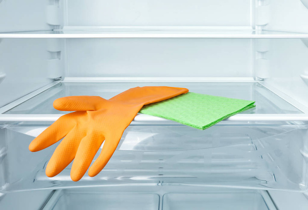 Cleaning rag and protective glove on refrigerator shelf - Φωτογραφία, εικόνα