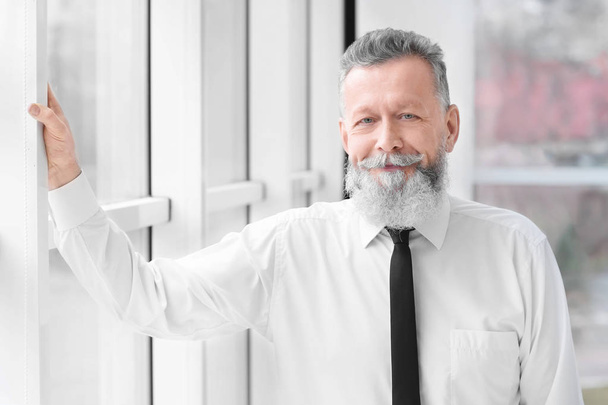 Portrait of confident mature man near window in office - Zdjęcie, obraz