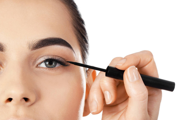 Professional visage artist applying makeup on woman's face against white background - Foto, imagen