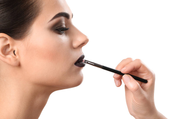Professional visage artist applying makeup on woman's face against white background - Fotoğraf, Görsel
