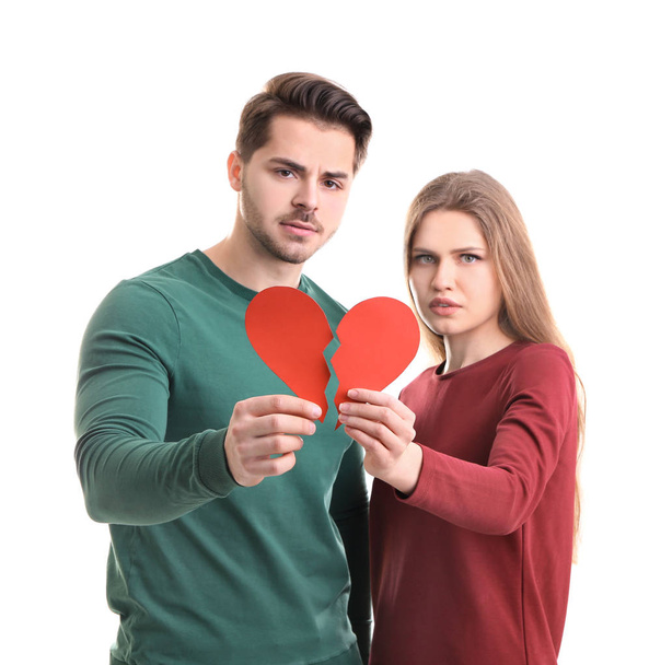 Young couple holding halves of broken heart on white background. Relationship problems - Фото, зображення