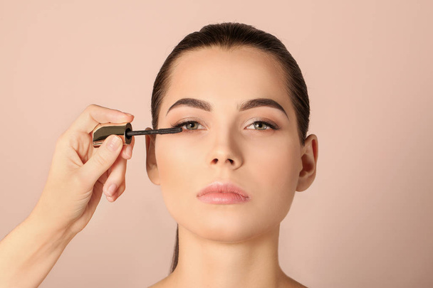 Professional visage artist applying makeup on woman's face against light background - Фото, изображение