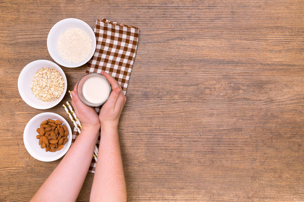 Plant alternative milk recipe: almond, oat, rice in woman hands on the wood background - Foto, Imagem