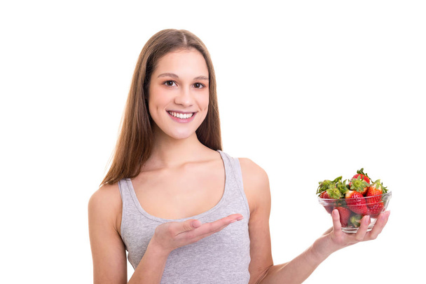 Krásná mladá žena držící nějaké jahody, izolované na bílém pozadí - Fotografie, Obrázek