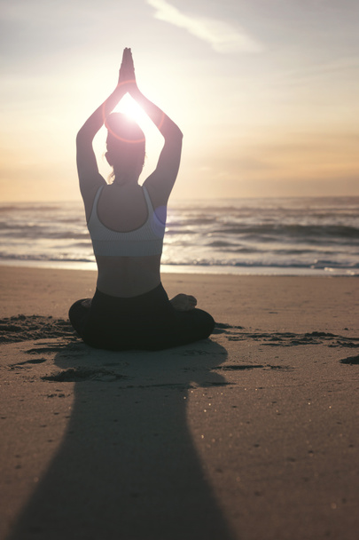 Σιλουέτα του σπορ νεαρή γυναίκα που κάνει την πρακτική της γιόγκα στην παραλία, την έννοια της υγιούς ζωής και τη φυσική ισορροπία μεταξύ σώματος και νοητική ανάπτυξη - Φωτογραφία, εικόνα