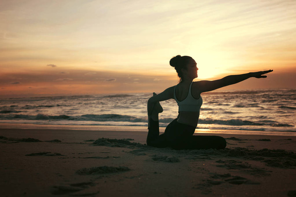 Silhouette de jeune femme sportive pratiquant le yoga à la plage, concept de vie saine et équilibre naturel entre le corps et le développement mental
 - Photo, image