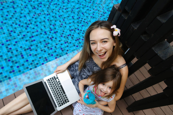 Gros plan de la mère, fille et ordinateur portable sur fond de piscine
 - Photo, image