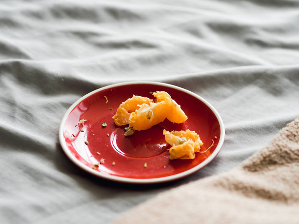 Left over of orange in red dish on bed on good relax day. - Fotó, kép