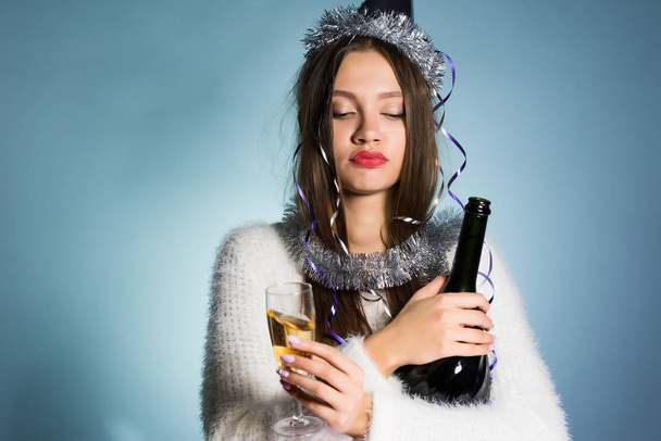 drunk woman in a festive cap holding a bottle of champagne - Фото, изображение