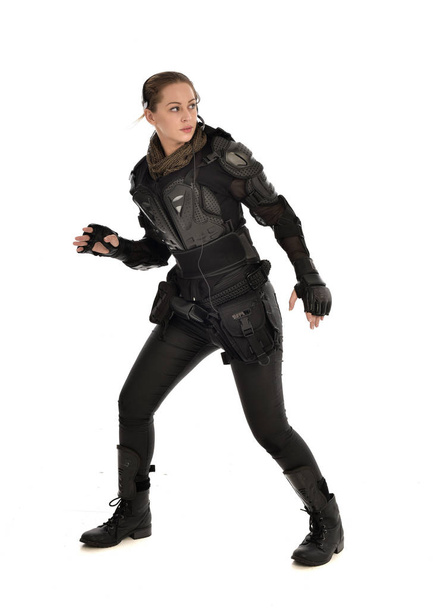 volledige lengte portret van vrouwelijke soldaat het dragen van zwarte tactische pantser, geïsoleerd op witte studio achtergrond. - Foto, afbeelding