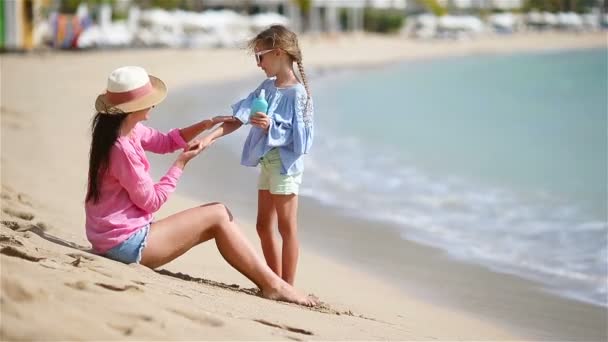 Mladá matka použití sluneční krém pro kid ruku venku na tropické pláži - Záběry, video