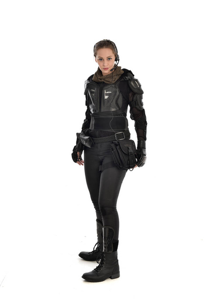 volledige lengte portret van vrouwelijke soldaat het dragen van zwarte tactische pantser, geïsoleerd op witte studio achtergrond. - Foto, afbeelding
