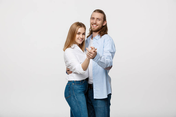 Jeune couple élégant en tissu décontracté dansant sur Isolé sur fond de studio blanc
. - Photo, image