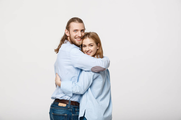 Retrato de alegre pareja joven de pie y abrazándose unos a otros sobre un fondo blanco aislado
 - Foto, imagen